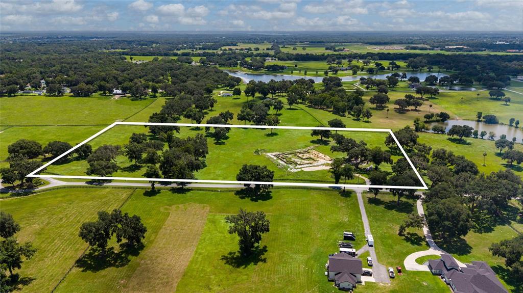 An aerial view shows a rectangular plot of land with scattered trees and a foundation — 15479 SE 57TH TERRACE, SUMMERFIELD, FL