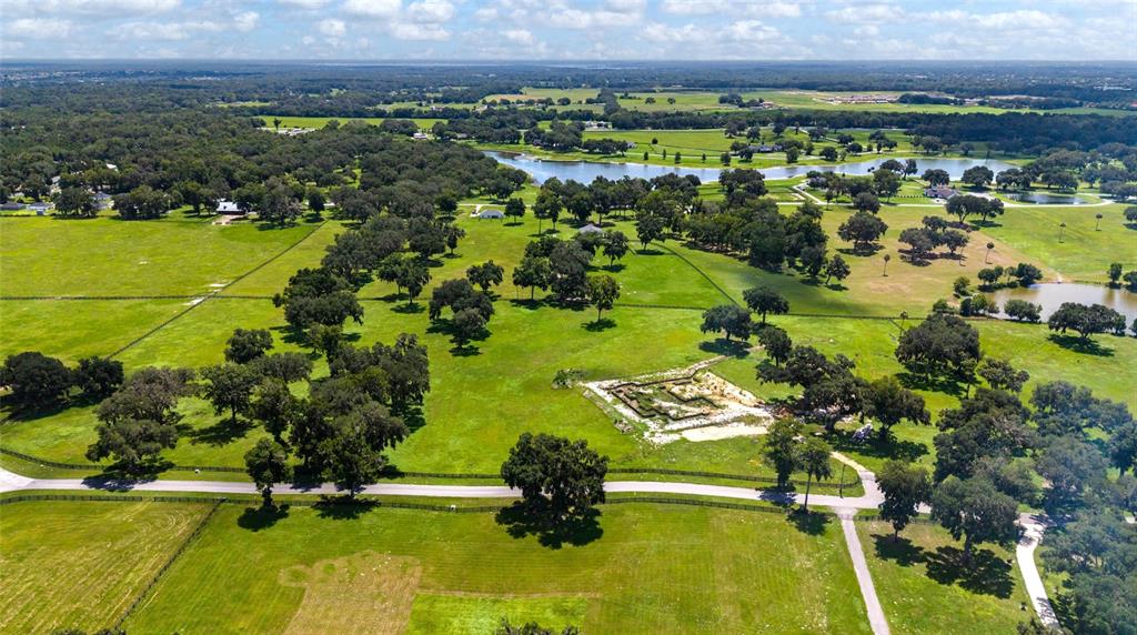 An aerial view shows a large, grassy rural property with scattered trees and a pond — 15479 SE 57TH TERRACE, SUMMERFIELD, FL