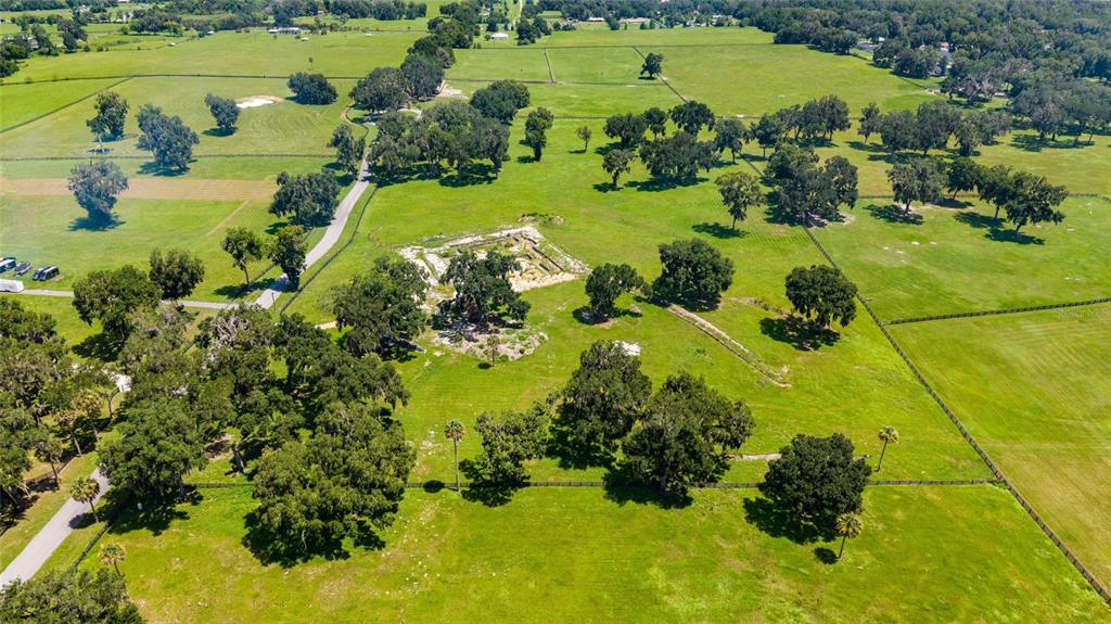 An aerial view shows a large, grassy pasture with scattered oak trees and fenced paddocks — 15479 SE 57TH TERRACE, SUMMERFIELD, FL