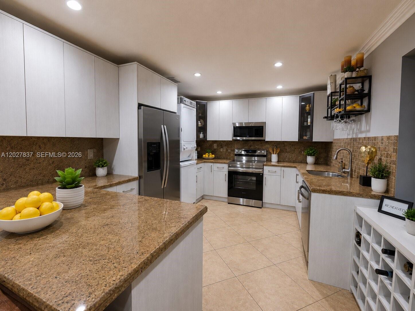 A kitchen features white cabinets, granite countertops, stainless steel appliances, and a stacked laundry unit — 7513 Grant Ct # A, Hollywood FL 33024, HOLLYWOOD, FL