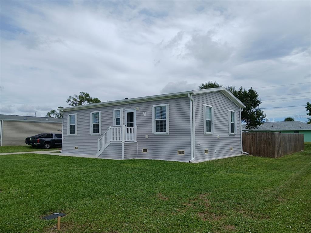 A light gray manufactured home with white trim sits on a grassy lot — 167 VIA MADONNA, ENGLEWOOD, FL