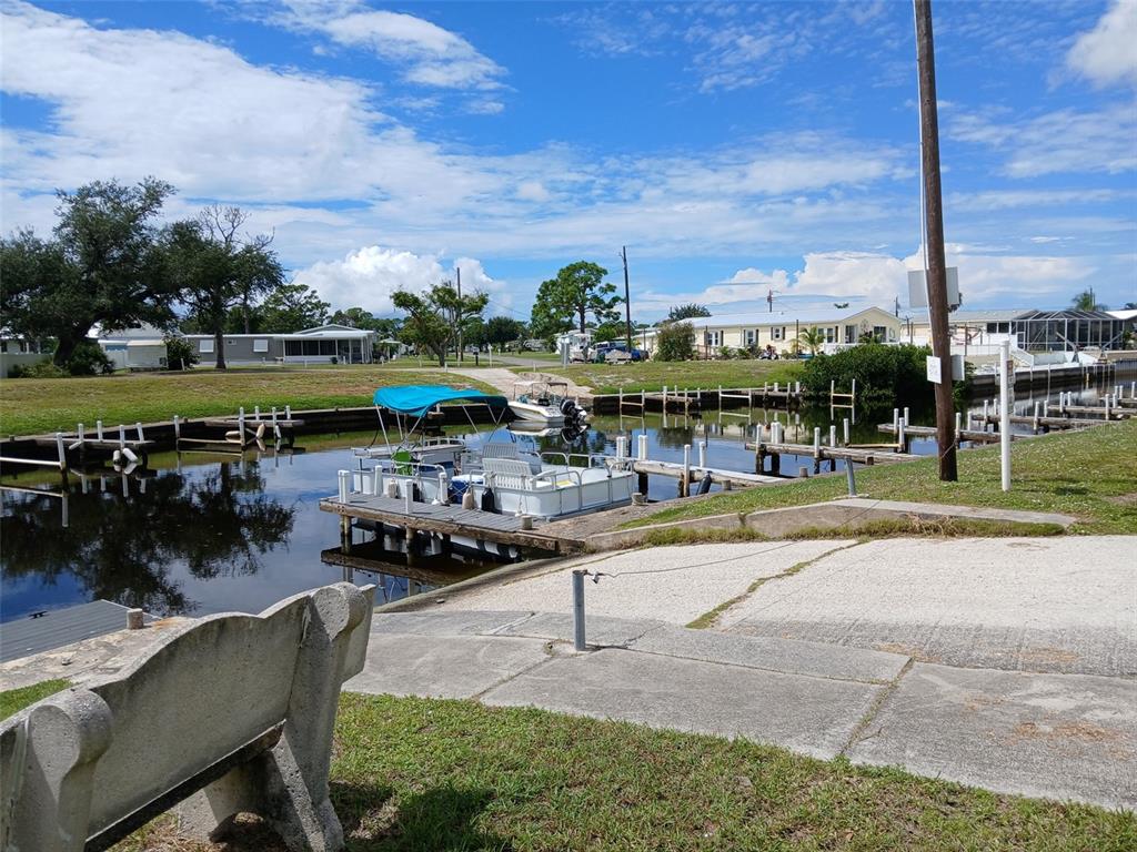 A boat ramp leads to a canal with a dock and a pontoon boat — 167 VIA MADONNA, ENGLEWOOD, FL