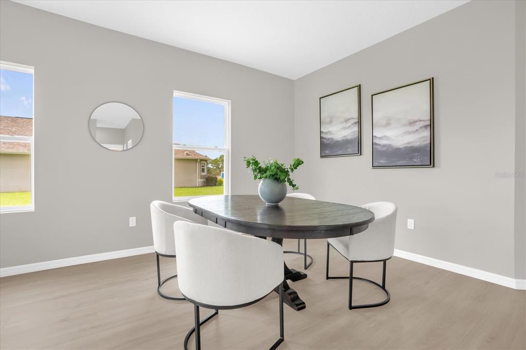 A dining room features a dark oval table, four white chairs, and two framed prints — 5834 ESCALON DRIVE, SEBRING, FL
