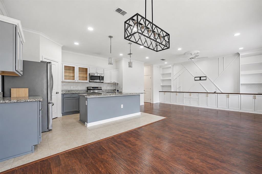 A kitchen with gray cabinets and a central island opens into a large living area — 2270 HEMINGWAY CIRCLE, GROVELAND, FL