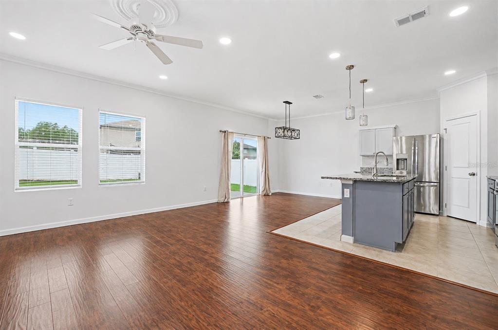 An open-concept living area with wood-look flooring, a kitchen island, and sliding glass doors — 2270 HEMINGWAY CIRCLE, GROVELAND, FL