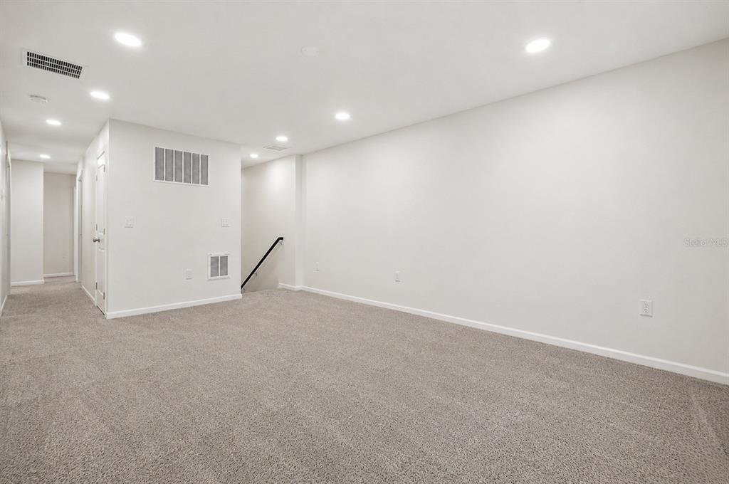 A spacious, carpeted room with white walls, recessed lighting, and a staircase leading downward — 2270 HEMINGWAY CIRCLE, GROVELAND, FL