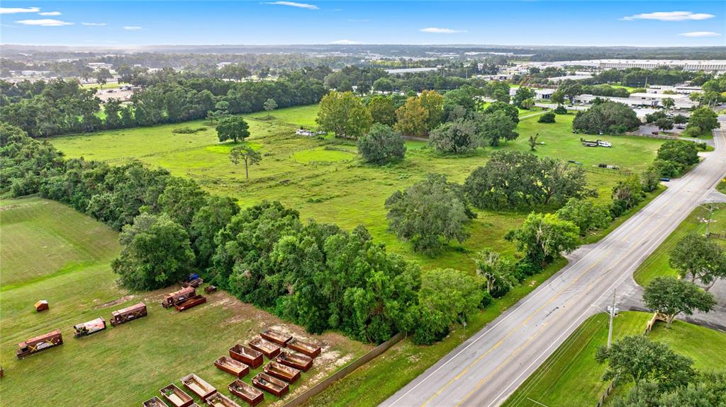 An aerial view shows a large grassy field with scattered trees and numerous dumpsters — NW 52ND AVENUE, OCALA, FL