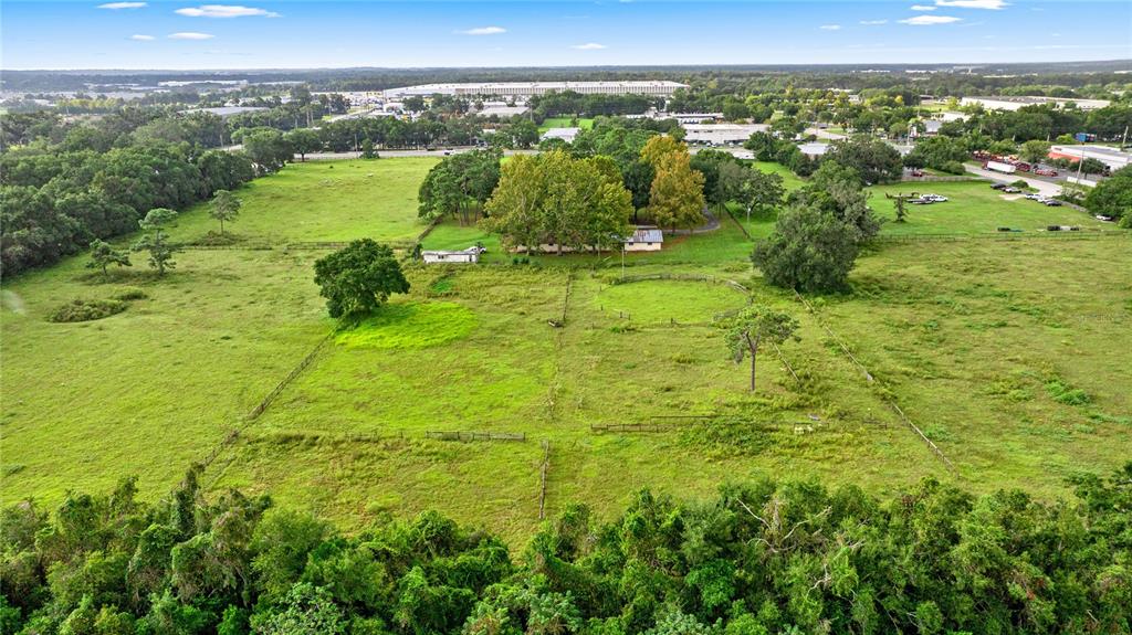 An aerial view of a rural property featuring a house, pastures, and fenced paddocks — NW 52ND AVENUE, OCALA, FL