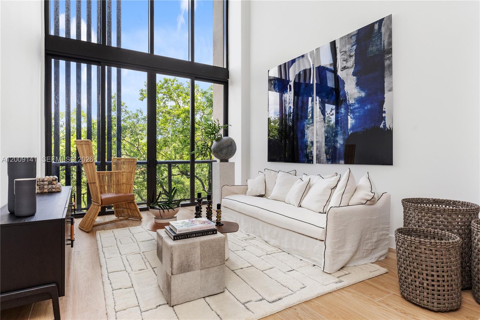 A bright living room features a white sofa, a woven chair, and large floor-to-ceiling windows — 3034 Oak Avenue, Coconut Grove FL 33133, COCONUT GROVE, FL