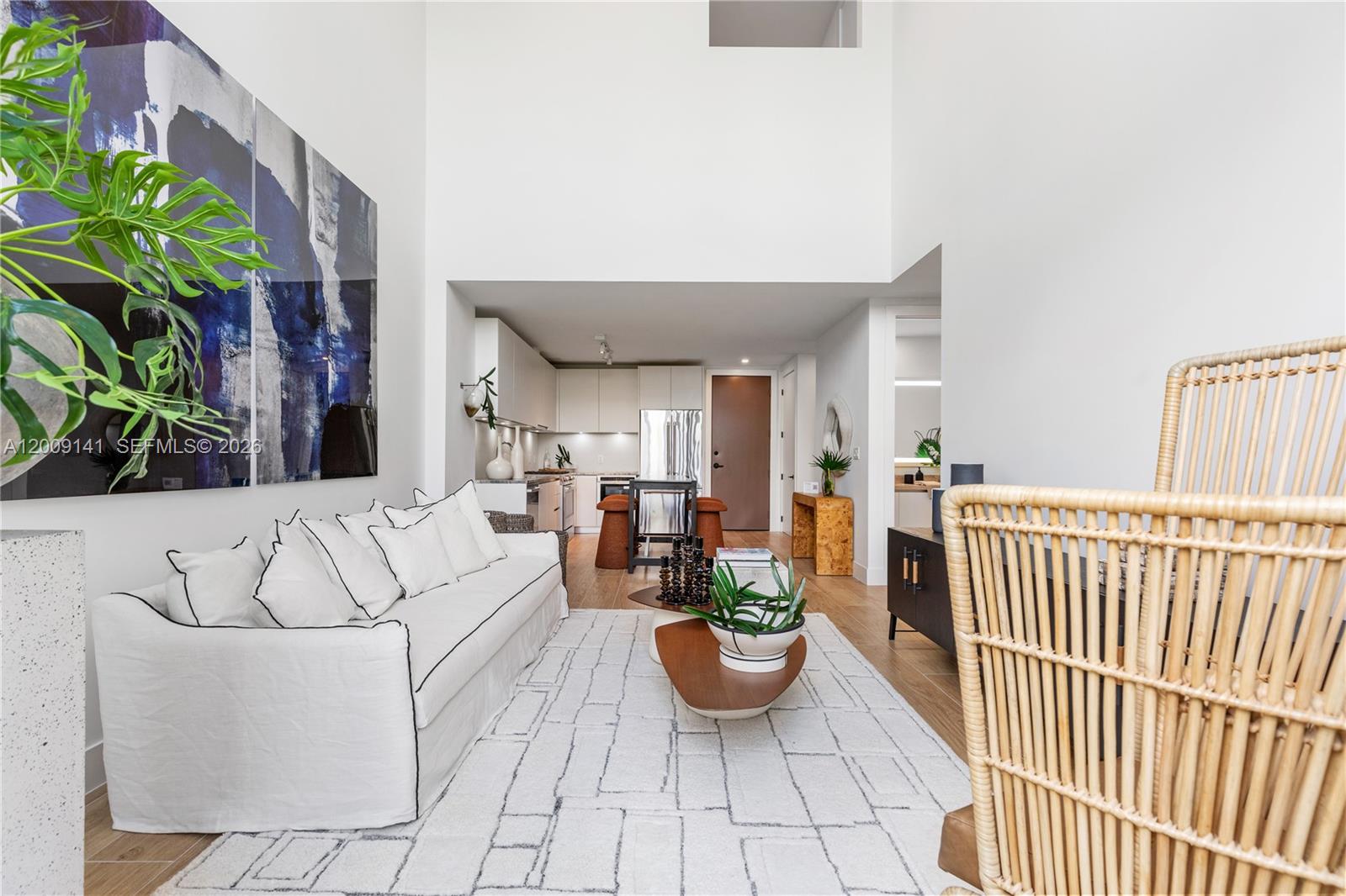 A living room with a white sofa, area rug, and high ceilings leads to a kitchen — 3034 Oak Avenue, Coconut Grove FL 33133, COCONUT GROVE, FL