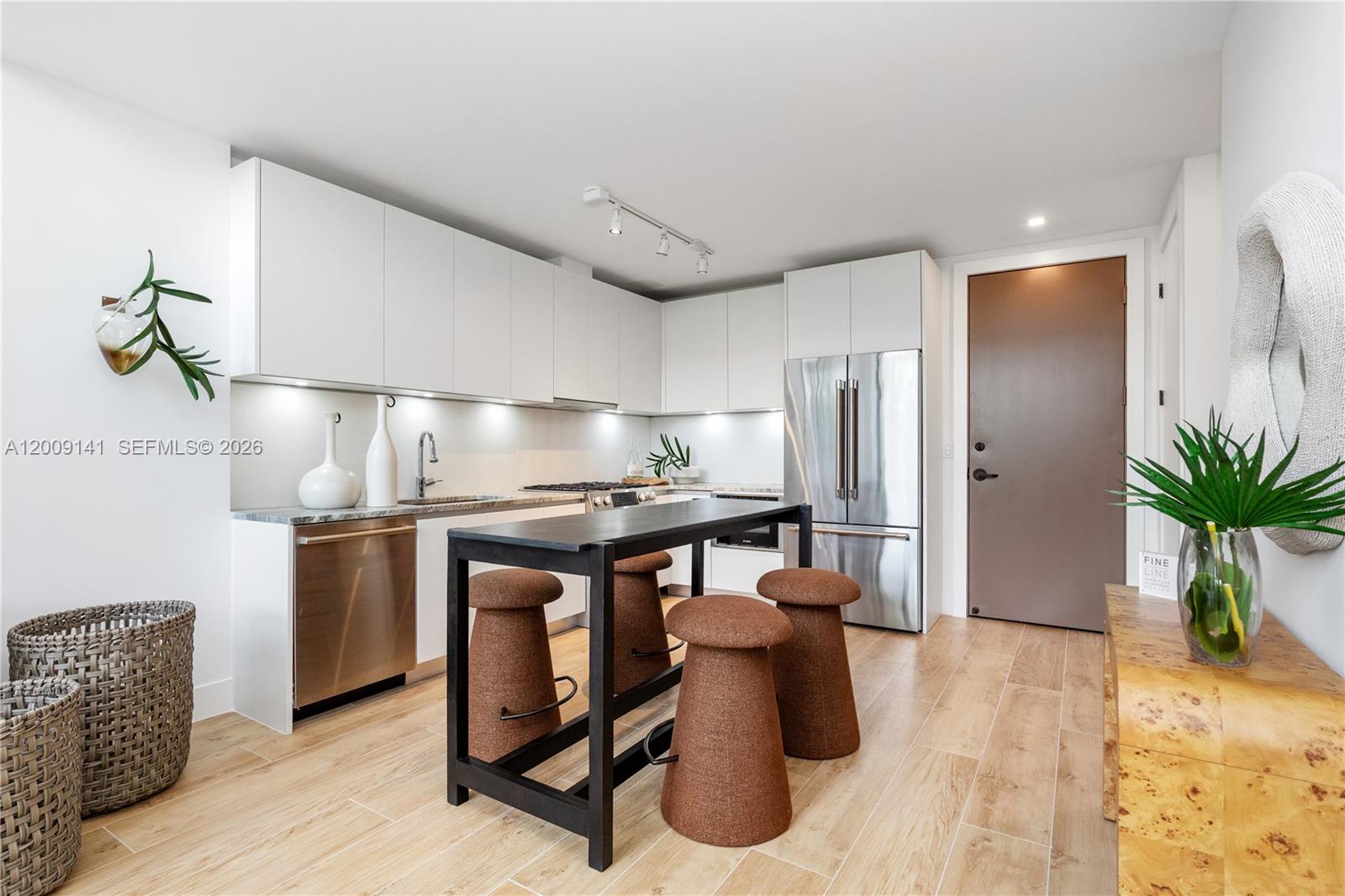 A modern kitchen features white cabinetry, stainless steel appliances, a black island, and wood flooring — 3034 Oak Avenue, Coconut Grove FL 33133, COCONUT GROVE, FL