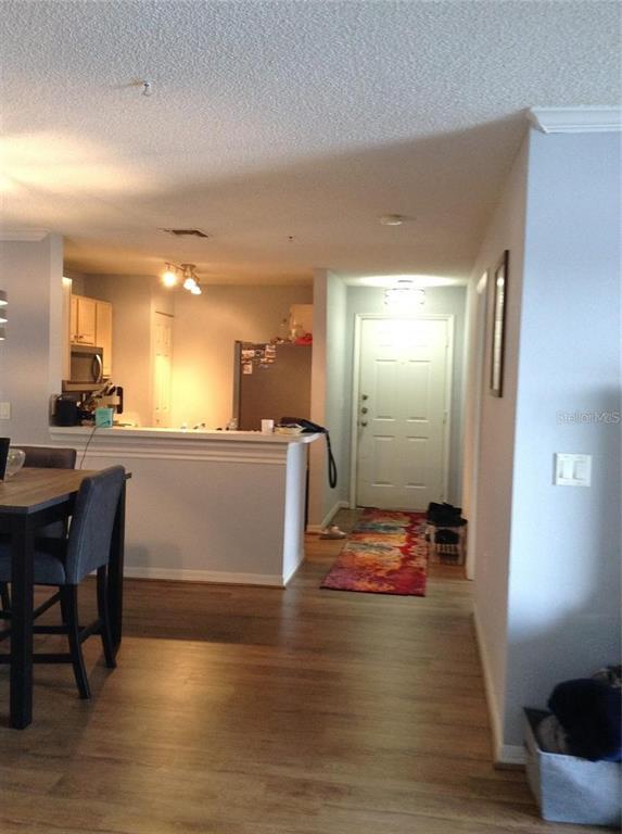 An open-concept kitchen with light wood cabinets overlooks a dining area and entryway — 1919 SUMMER CLUB DRIVE UNIT 207, OVIEDO, FL