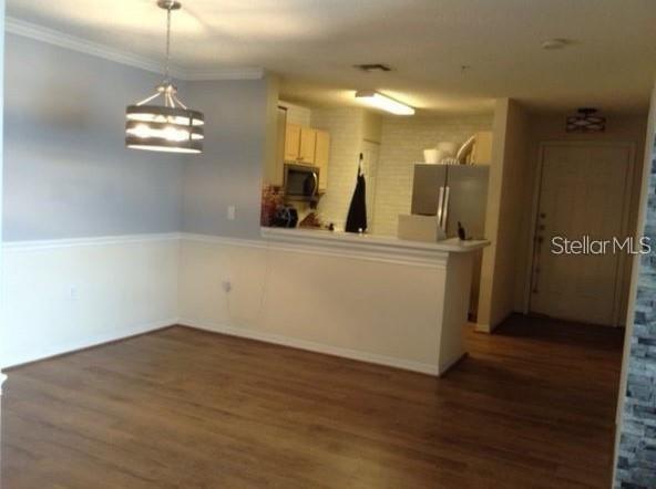 An open-concept dining area with wood-look flooring leads into a kitchen with a breakfast bar — 1919 SUMMER CLUB DRIVE UNIT 207, OVIEDO, FL