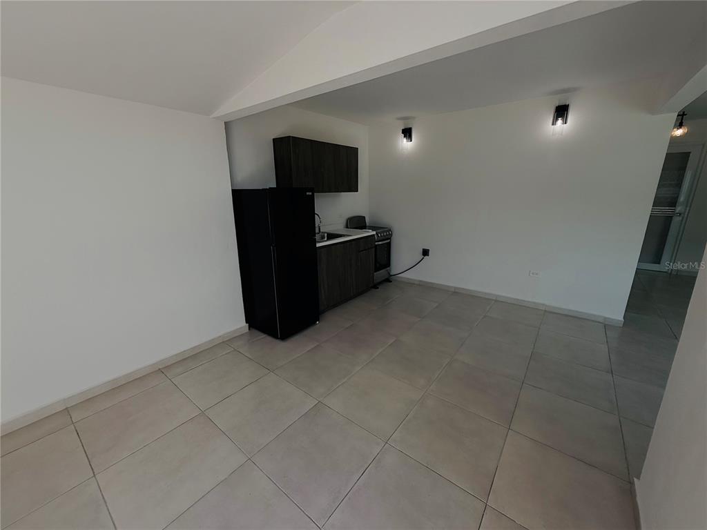 A small kitchen area features dark wood cabinets, a black refrigerator, and light tile flooring — TRIPLEX HOUSE  Calle 5 D1 EXT. BUSO, HUMACAO, PR