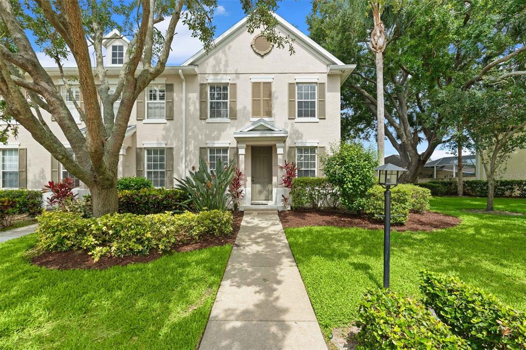 A two-story townhouse with a beige stucco exterior, tan shutters, and a concrete walkway — 5650 DUVAL STREET, BRADENTON, FL