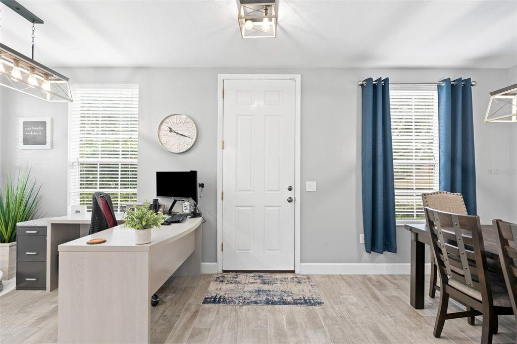 A bright room features a desk, a dining table, and a central white front door — 5650 DUVAL STREET, BRADENTON, FL