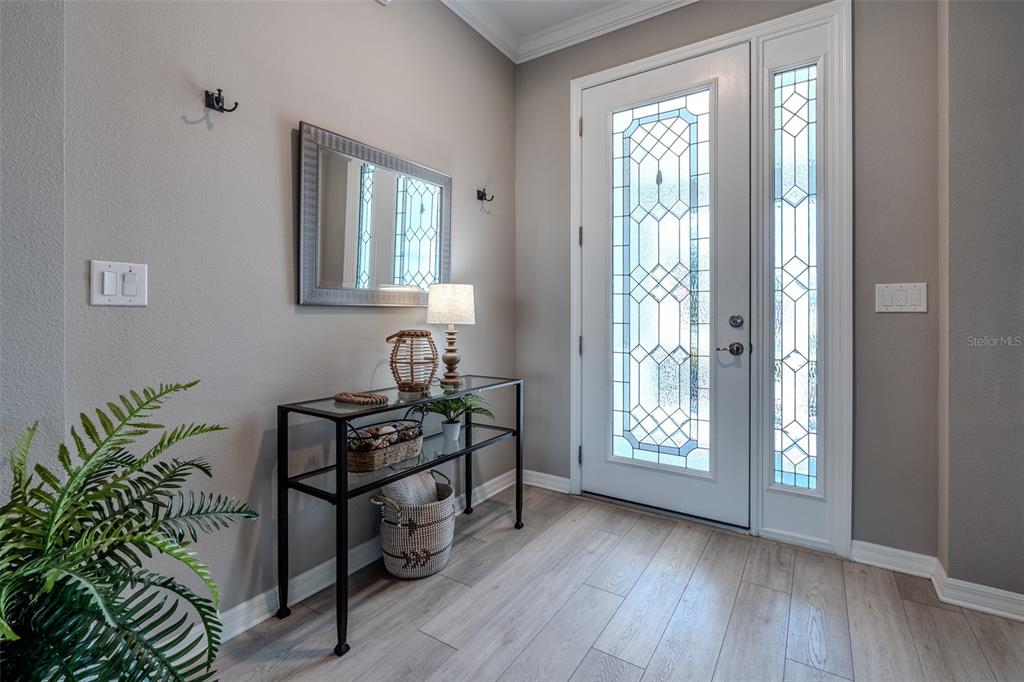 A bright entryway features a glass console table, a mirror, and a decorative front door — 10517 SW 90TH STREET ROAD, OCALA, FL