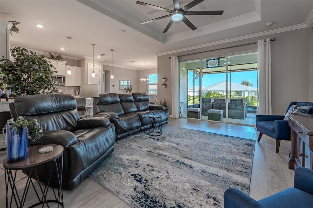 A living room with dark leather furniture, a blue area rug, and sliding glass doors — 10517 SW 90TH STREET ROAD, OCALA, FL