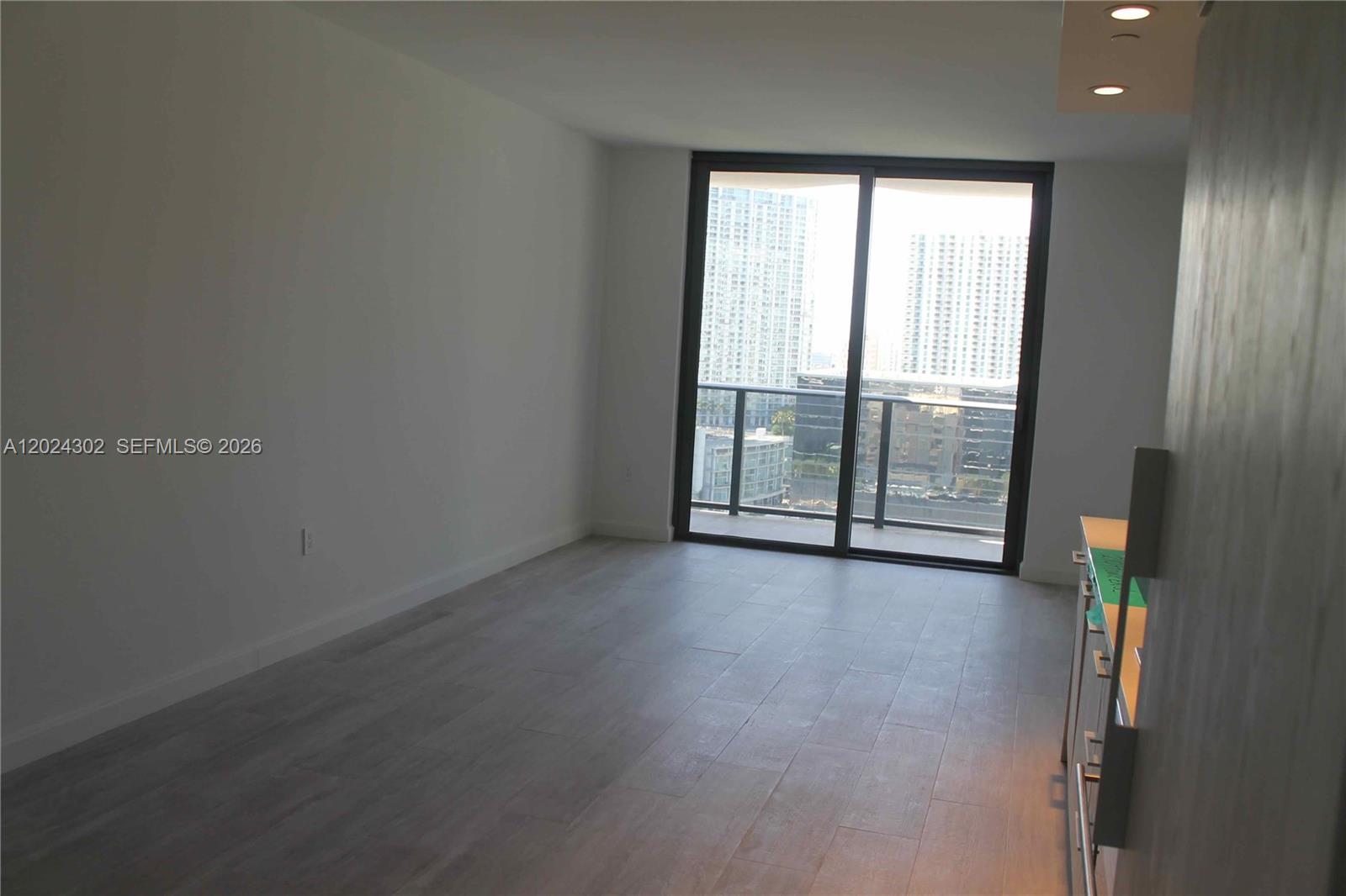 An empty room features light wood-look flooring, white walls, and a sliding glass balcony door — 45 SW 9th St # 2109, Miami FL 33130, MIAMI, FL