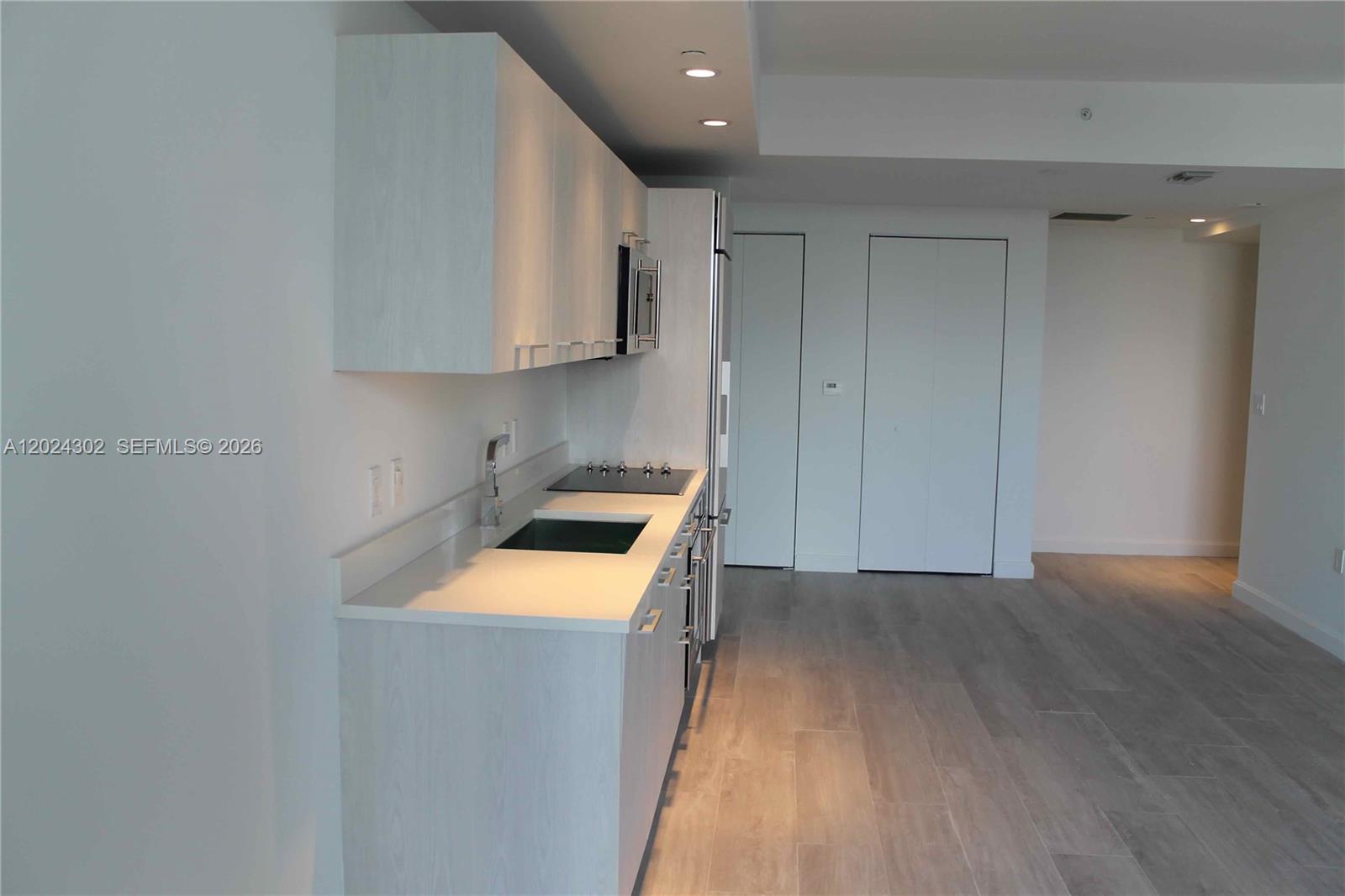 A modern kitchen features light wood cabinets, white countertops, and stainless steel appliances — 45 SW 9th St # 2109, Miami FL 33130, MIAMI, FL