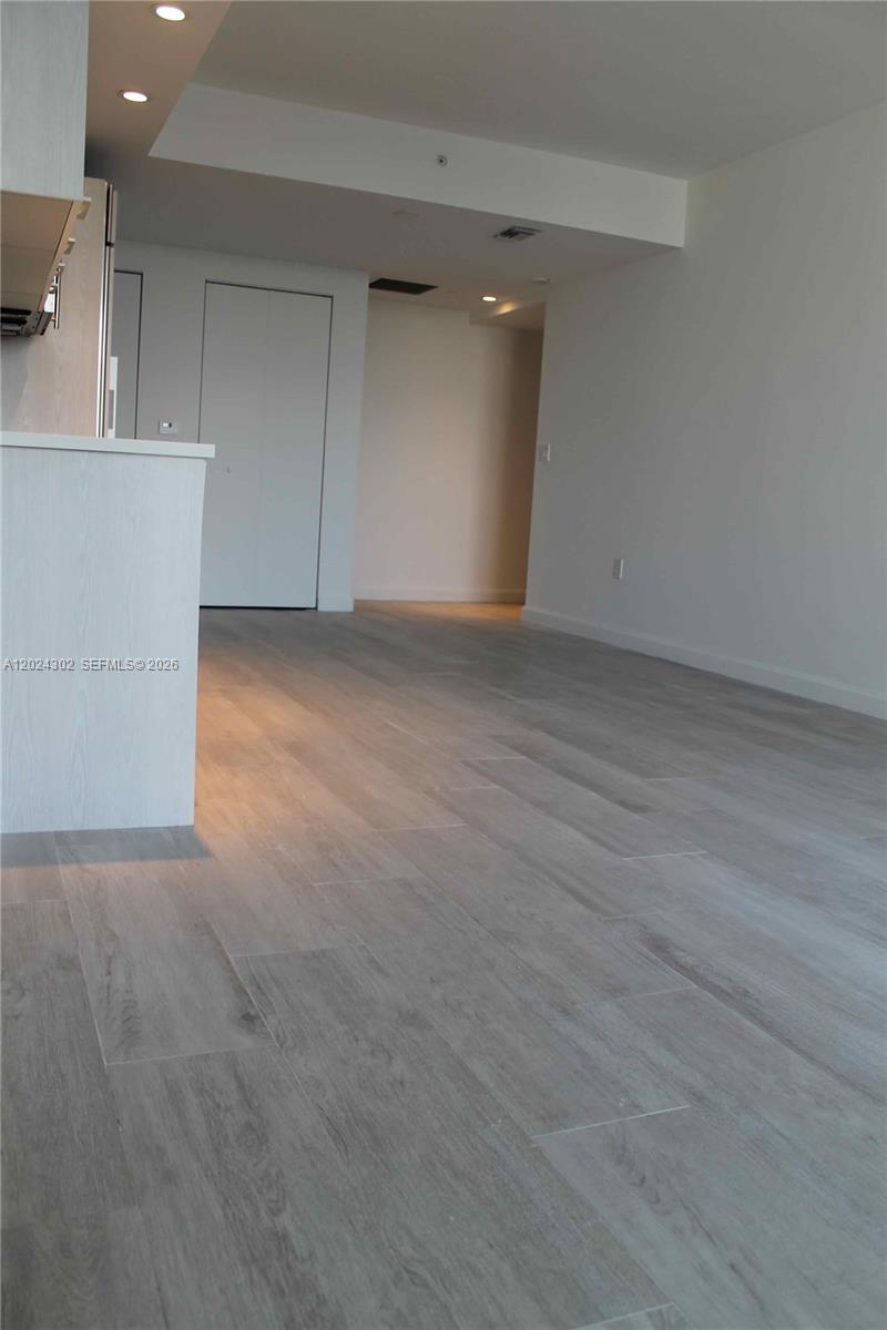 This interior view shows a kitchen island, light wood-look flooring, and a hallway — 45 SW 9th St # 2109, Miami FL 33130, MIAMI, FL