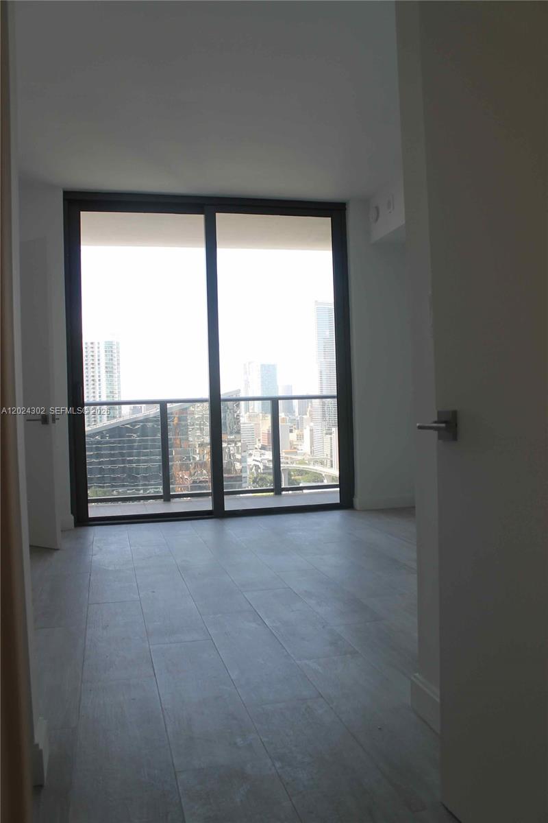 A room with light-colored tile flooring and a sliding glass door leading to a balcony — 45 SW 9th St # 2109, Miami FL 33130, MIAMI, FL