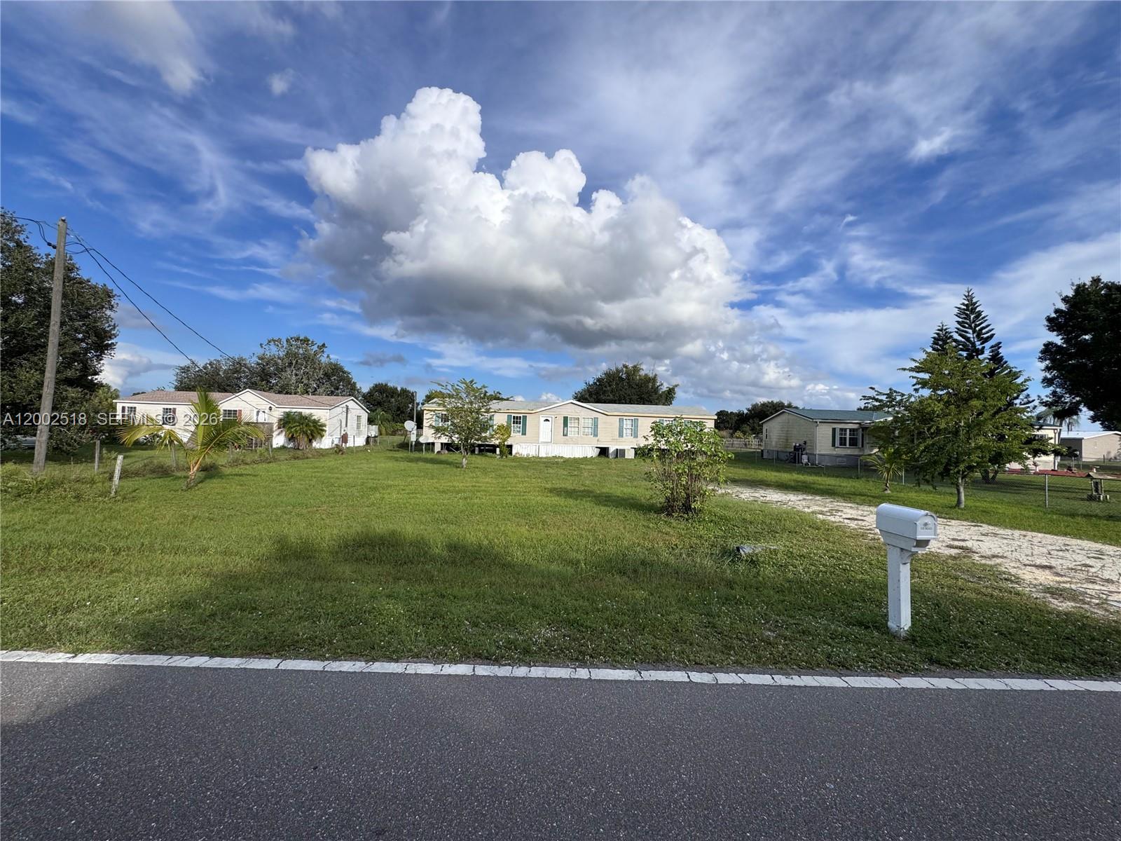 A wide-angle exterior view shows a mobile home situated on a large, grassy lot — 866 NE 104, Okeechobee FL 34972, OKEECHOBEE, FL