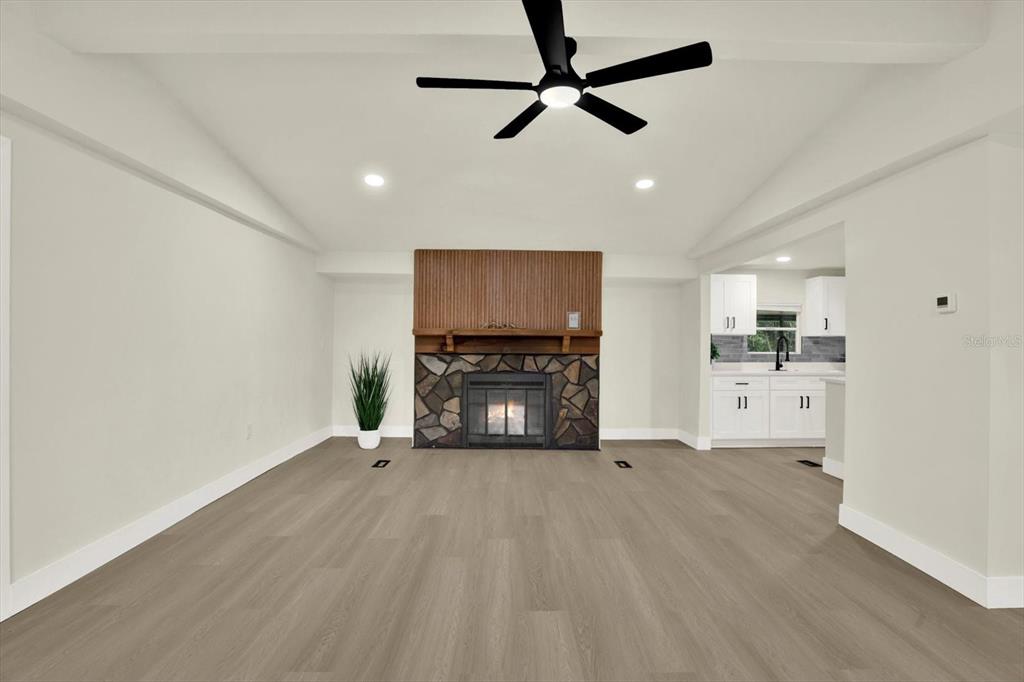 A living room features a stone fireplace, wood-slat accent wall, and light-colored wood flooring — 5801 MYRTLE LANE, TAMPA, FL