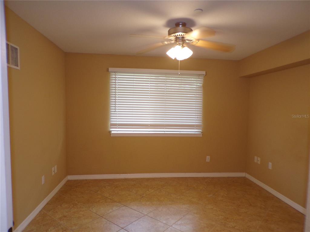 An empty room with tan walls, tile flooring, a ceiling fan, and a window with blinds — 150 HARBORSIDE AVENUE UNIT 133, PUNTA GORDA, FL