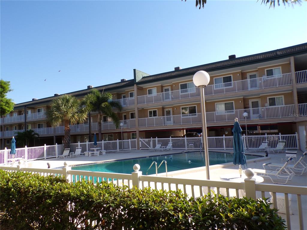A multi-story apartment building overlooks a swimming pool enclosed by a white fence — 150 HARBORSIDE AVENUE UNIT 133, PUNTA GORDA, FL