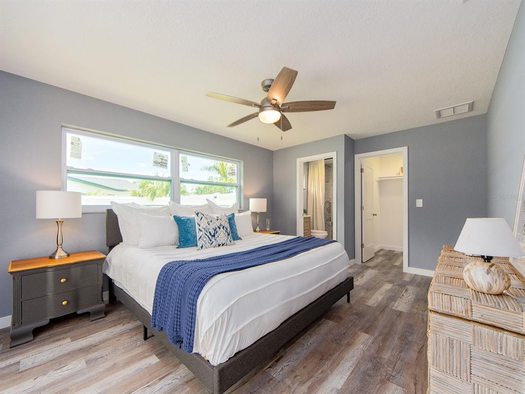 A bedroom features gray walls, wood-look flooring, a ceiling fan, and an attached bathroom — 201 HARBOR BLUFF DRIVE, LARGO, FL