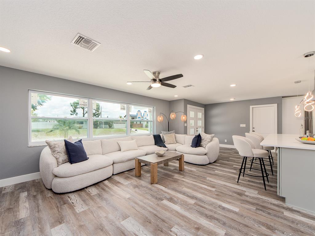 A living room features a large white sectional sofa, wood coffee table, and gray flooring — 201 HARBOR BLUFF DRIVE, LARGO, FL