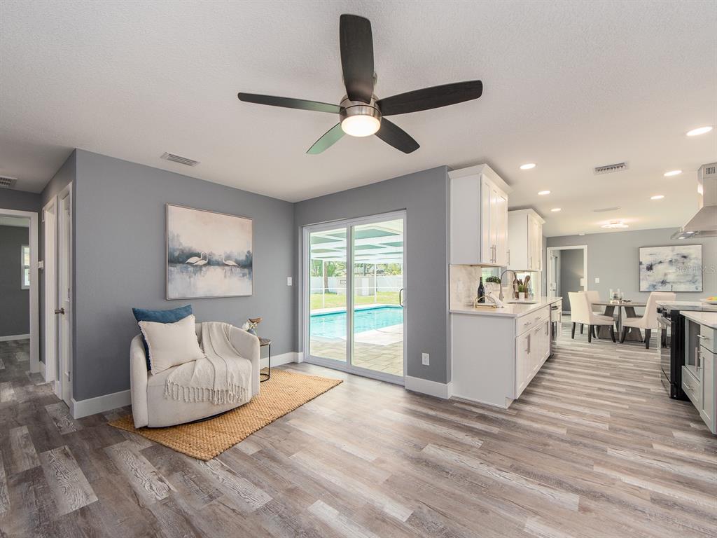 A living area with gray walls, wood-look flooring, a ceiling fan, and a sliding glass door — 201 HARBOR BLUFF DRIVE, LARGO, FL