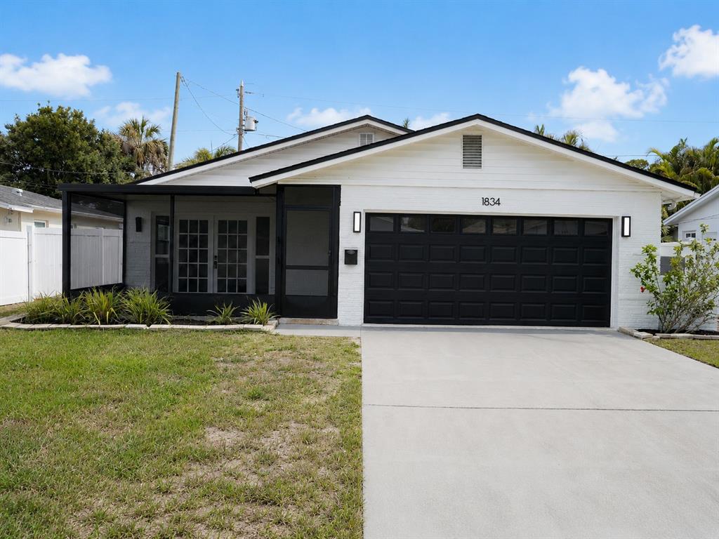 A white brick house with a black garage door and a screened-in front porch — 1834 NEW HAMPSHIRE AVENUE NE, ST PETERSBURG, FL