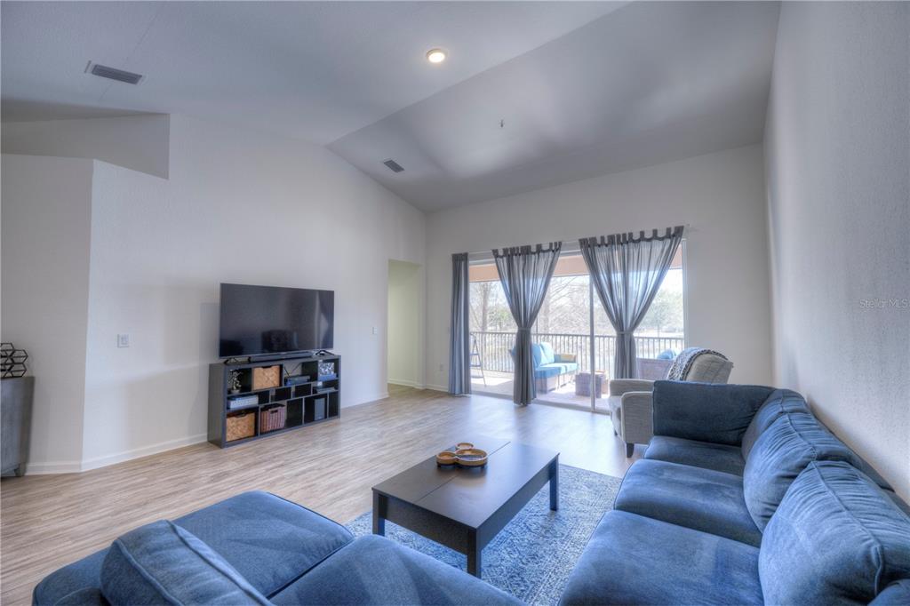 A living room features a blue sectional sofa, a television on a shelf, and sliding glass doors — 8318 FOSTER DRIVE UNIT 8318, DAVENPORT, FL