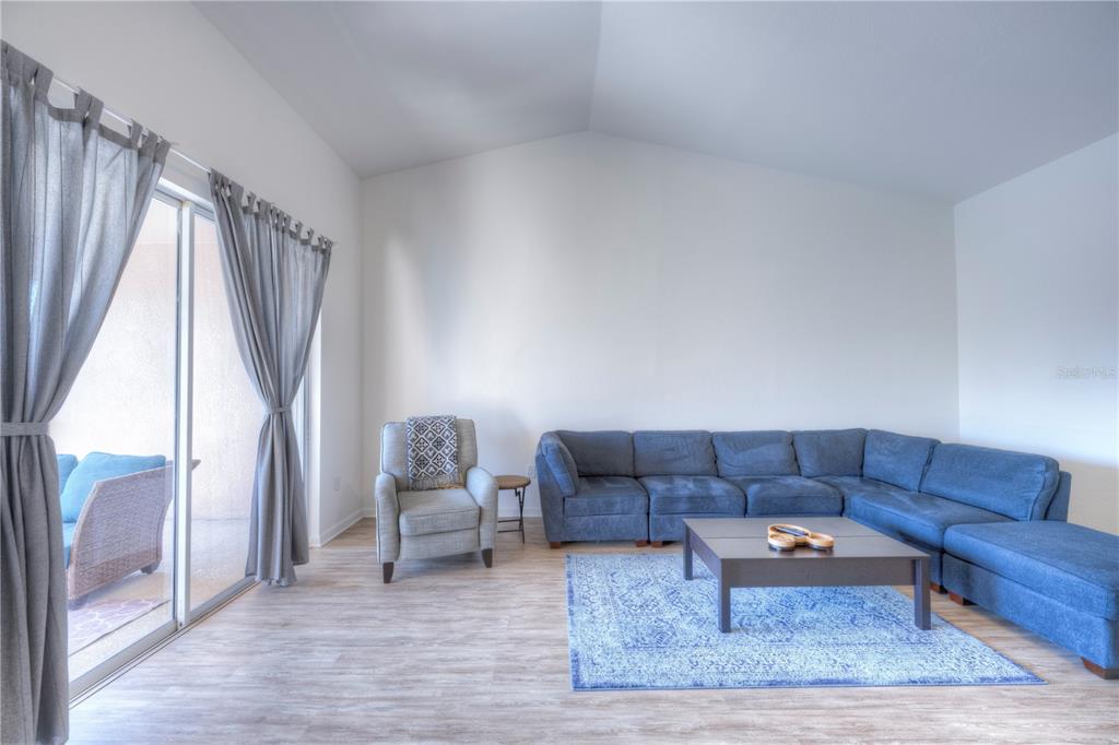A living room features a blue sectional sofa, a gray armchair, and a sliding glass door — 8318 FOSTER DRIVE UNIT 8318, DAVENPORT, FL