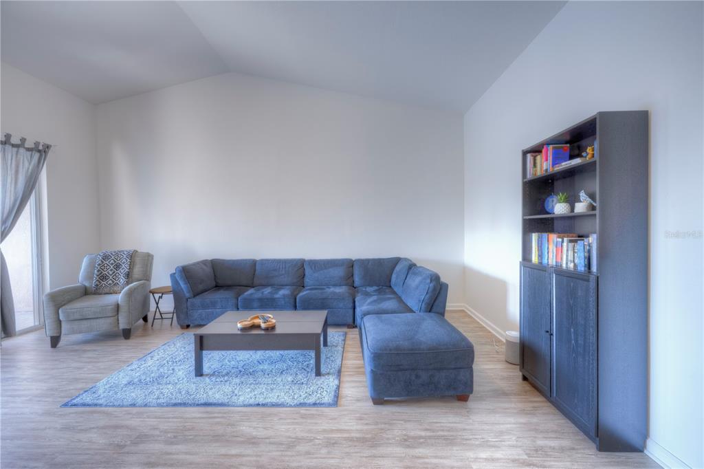 A living room features a blue sectional sofa, a coffee table, and a dark bookshelf — 8318 FOSTER DRIVE UNIT 8318, DAVENPORT, FL