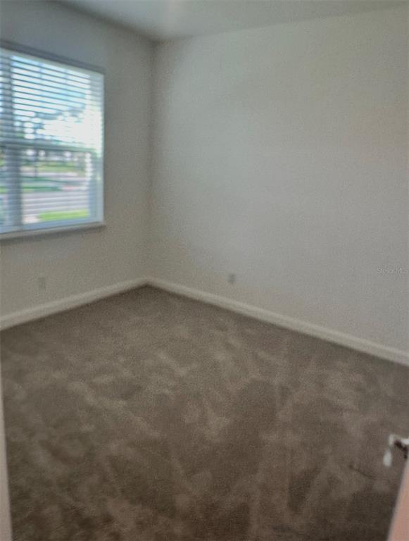 An empty bedroom features beige carpet, white walls, and a window with horizontal blinds — 12113 VIA CASELLI LANE, WINDERMERE, FL