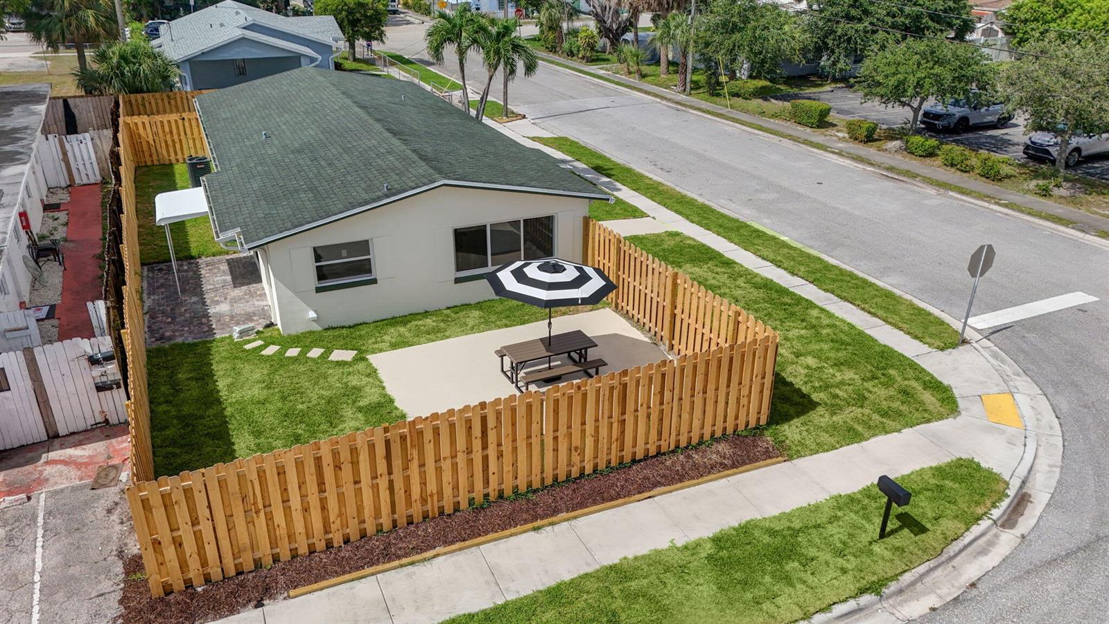 An aerial view shows a house with a fenced yard, patio, and picnic table — 665 W 7th Street, Riviera Beach FL 33404, RIVIERA BEACH, FL