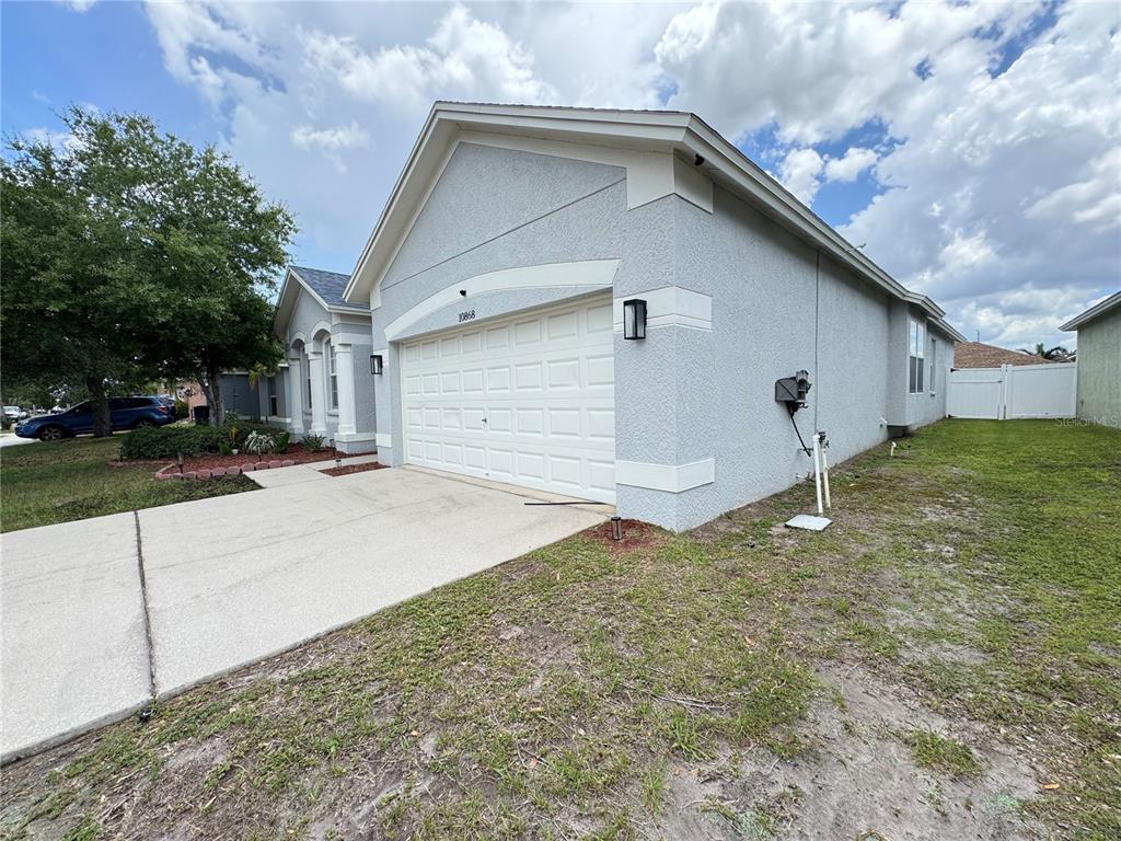 A light-colored stucco house features a two-car garage and a concrete driveway — 10868 STANDING STONE DRIVE, WIMAUMA, FL