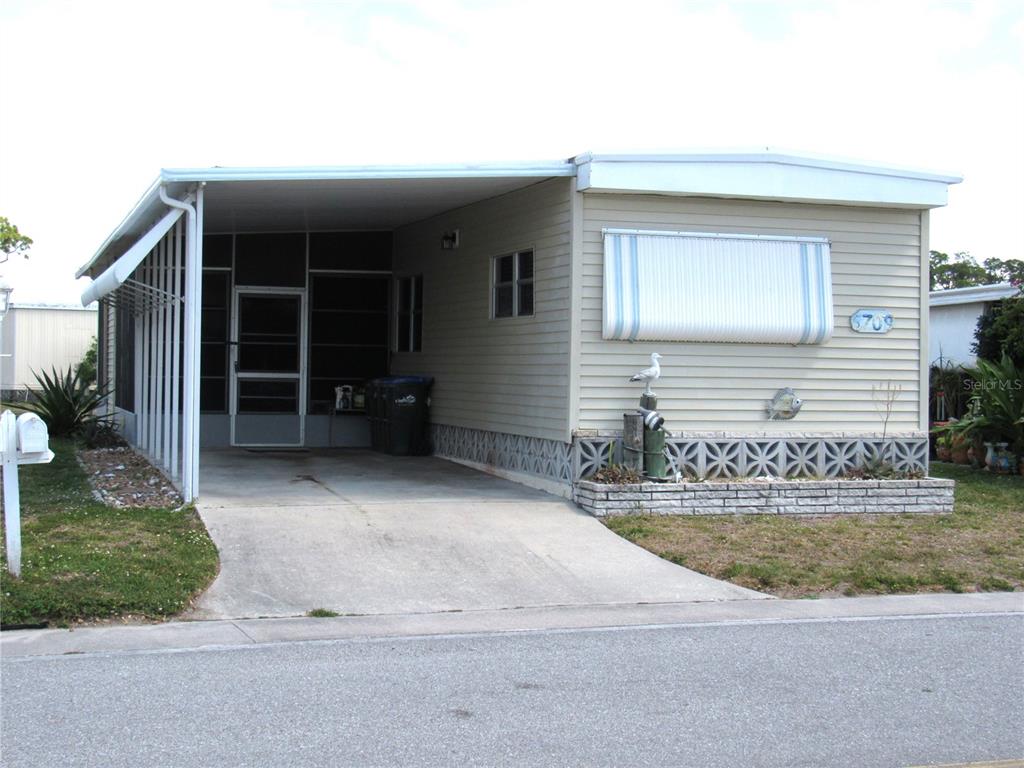 A single-story manufactured home with a carport, screened porch, and decorative concrete block skirting — 5709 HOLIDAY PARK BOULEVARD, NORTH PORT, FL
