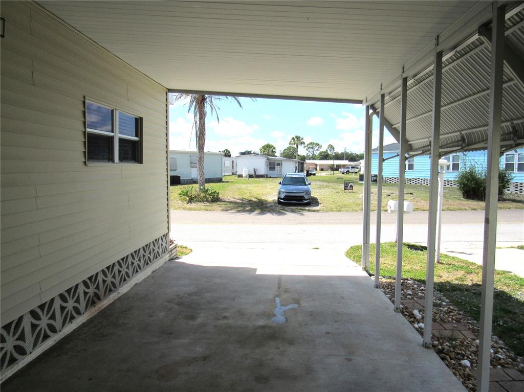 A concrete carport with a metal roof and support posts overlooks a residential street — 5709 HOLIDAY PARK BOULEVARD, NORTH PORT, FL