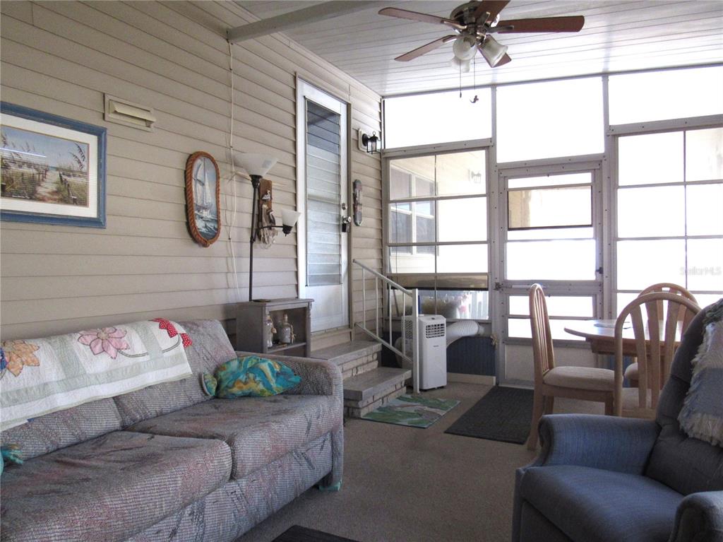 A sunroom features a sofa, a recliner, a dining set, and a portable air conditioner — 5709 HOLIDAY PARK BOULEVARD, NORTH PORT, FL