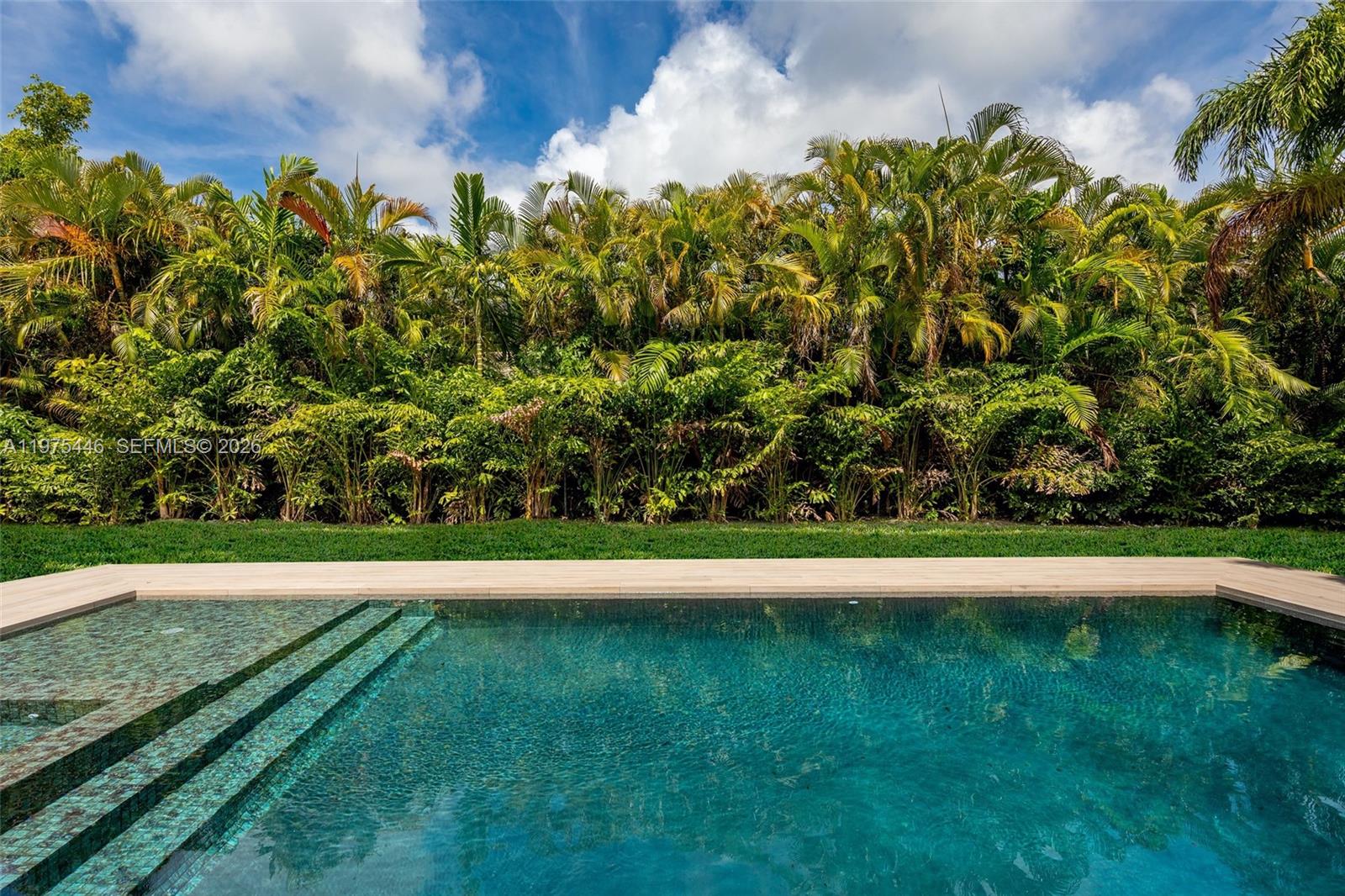 A swimming pool with tiled steps sits in front of a dense row of palm trees — 13306 SW 58th Ct, Pinecrest FL 33156, PINECREST, FL