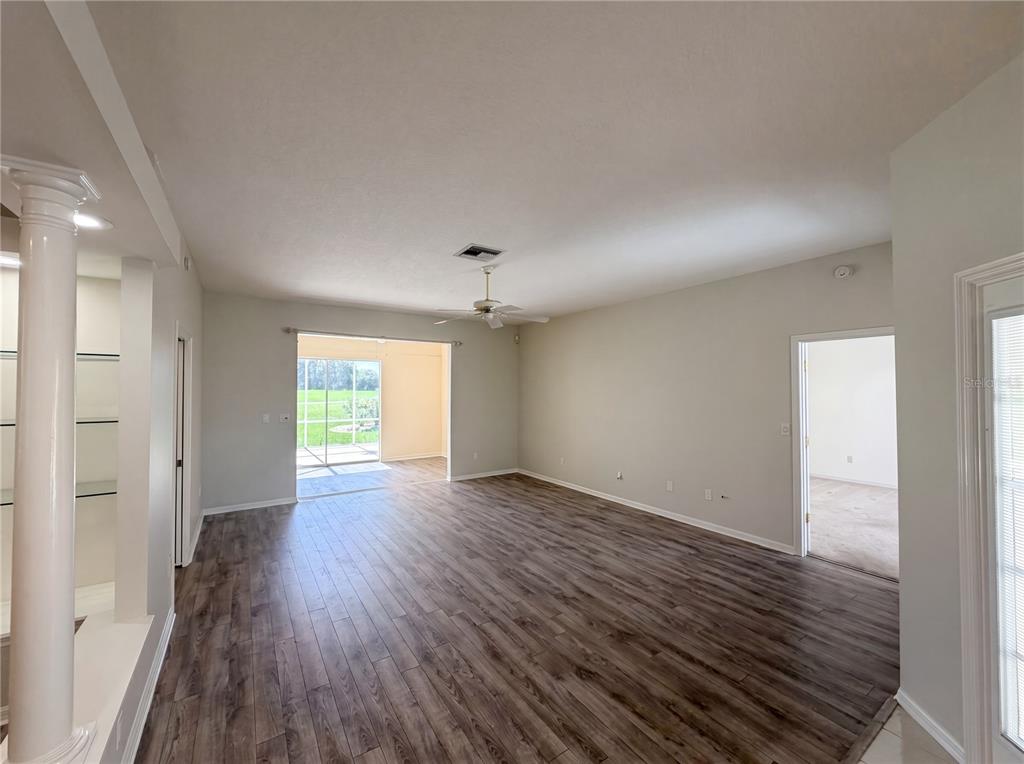 An open living area features wood-look flooring, a ceiling fan, and a sliding glass door — 3608 CREEKSIDE DRIVE, SEBRING, FL