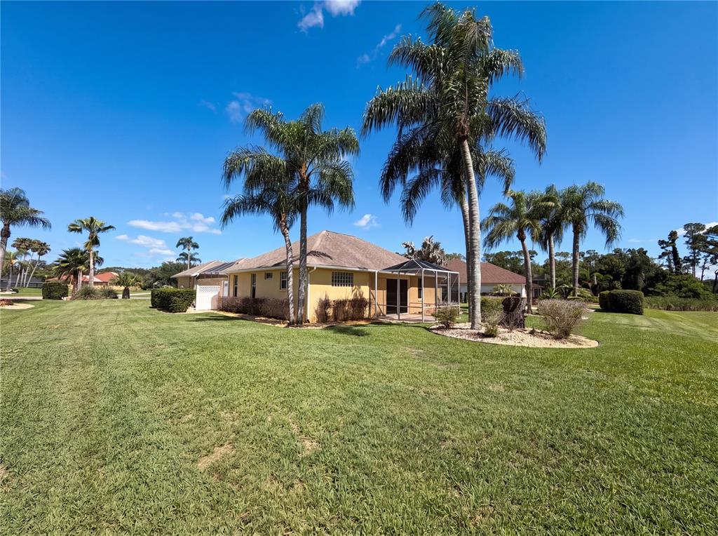 A yellow house with a screened-in patio sits on a large, grassy lawn — 3608 CREEKSIDE DRIVE, SEBRING, FL