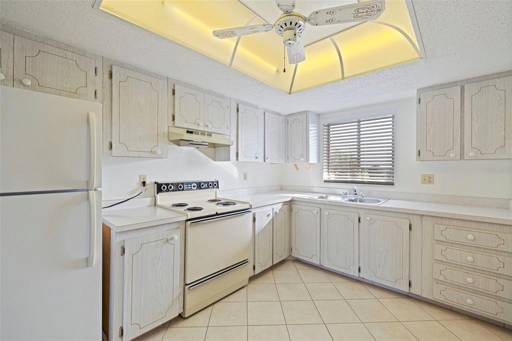 A kitchen with white appliances, light wood-grain cabinets, tile flooring, and a recessed ceiling light — 3408 LAKE BAYSHORE DRIVE UNIT P-317, BRADENTON, FL