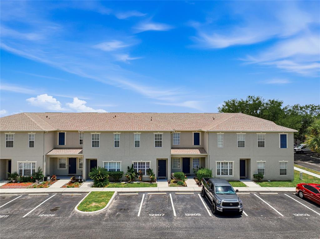 A two-story townhouse building with a parking lot in the foreground — 12907 KINGS CROSSING DRIVE, GIBSONTON, FL