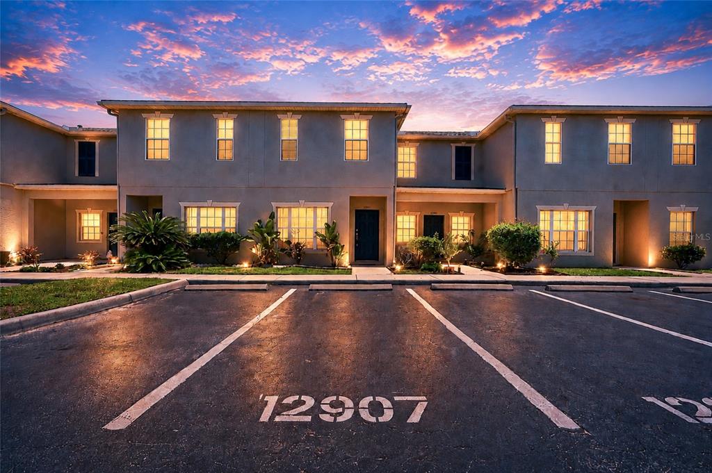 A two-story apartment building exterior at dusk with parking spaces in the foreground — 12907 KINGS CROSSING DRIVE, GIBSONTON, FL