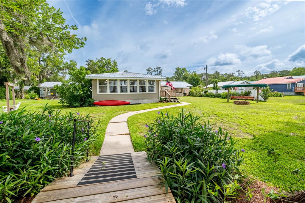 A wooden walkway leads through a grassy yard toward a house with a red kayak — 6600 SW 160TH STREET, STARKE, FL